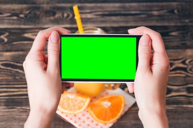 Portakal fotoğrafta eller. Yeşil ekran. Teknoloji kavramı