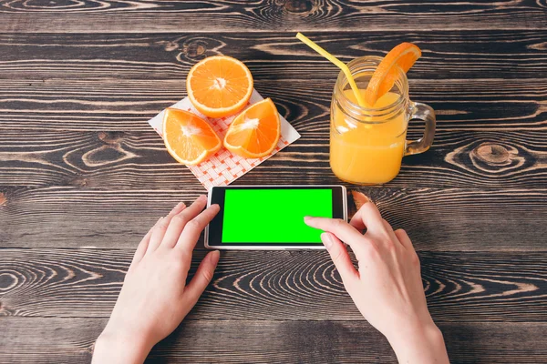 Mujer usando teléfono móvil contra naranjas de frutas. Concepto de tecnología . — Foto de Stock