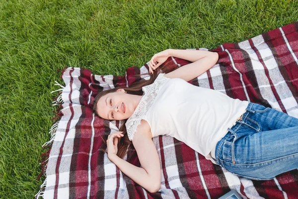 Молодая женщина с длинными волосами, лежащая на траве — стоковое фото