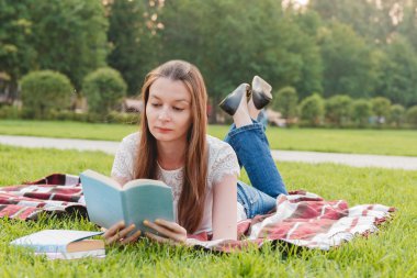 Genç kadın okuma kitabı Park'ta çim üzerinde yalan