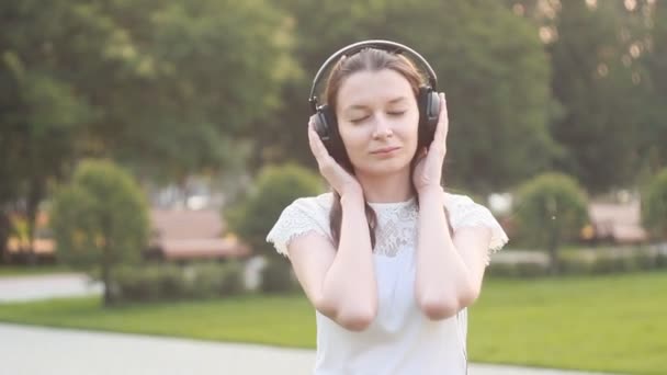 Jovem mulher branca morena com fones de ouvido ao ar livre — Vídeo de Stock
