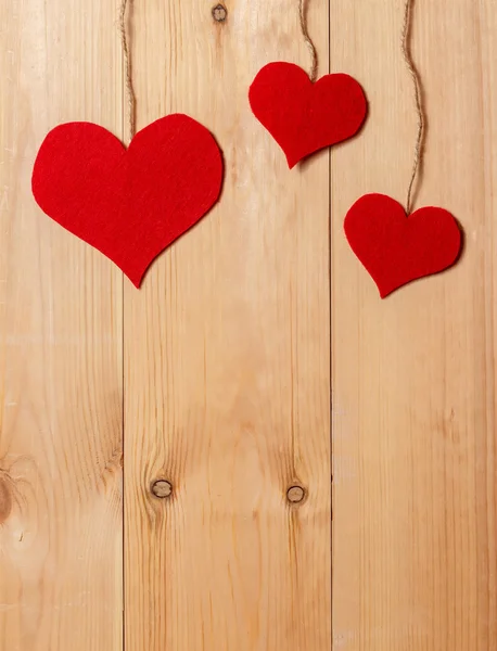 Corações artesanais pendurados na linha contra a parede de grãos de madeira — Fotografia de Stock