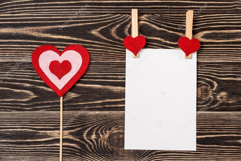Pins, red hearts, blank card on wooden background