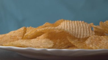 Çipler izole bir zemine düşüyor. Stok görüntüleri. Lezzetli cipsler düşer ve iştahı açar. Patates cipsi şeklinde zararlı atıştırmalıklar. En sevdiği abur cubur.
