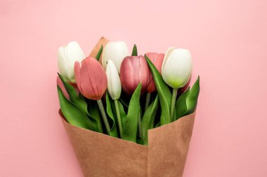 Pastel pembe kağıt arka planda bir buket güzel bahar lale çiçeği. Üst Manzara. Uluslararası Kadınlar Günü ya da Anneler Günü için tebrik kartı. Düz yatıyordu.