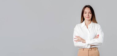 Açık gri arka planda kolları çapraz olan kendinden emin Ukraynalı iş kadını, web sitesi başlığı veya İnternet afişi için ideal.