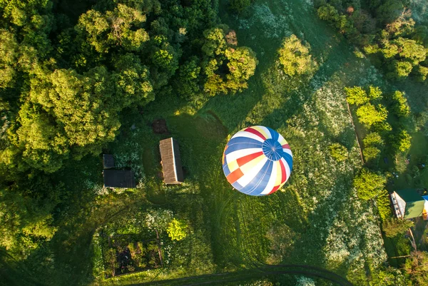 Воздушный шар летит над полем и дома — стоковое фото