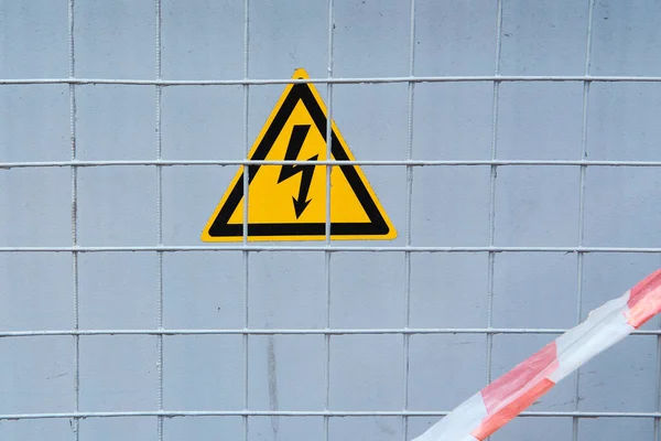 High voltage caution sign behind a metal grid. space for lettering or design