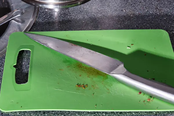 Eski plastik kesme tahtası ve mutfak bıçağı. Yakın plan. Sert gölgeler
