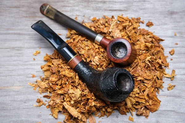 ぼんやりとした木製の背景にタバコの山の上に2本の煙管 選択的焦点 — ストック写真