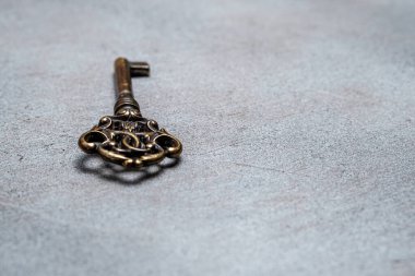Soyut gri arka planda eski bronz anahtar. Seçici odaklanma. Harfler ve tasarım için boşluk