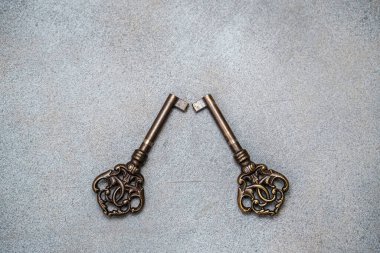 Soyut gri arka planda iki eski bronz anahtar. Yukarıdan bak. Harfler ve tasarım için boşluk