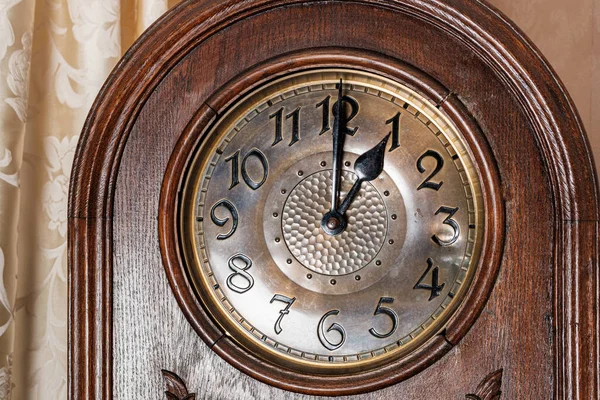 Fragment of an old clock showing one hour. Floor mechanical retro clock in a wooden case. Close-up.
