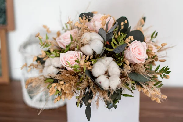 Long lasting flowers decoration. Preserved roses with dried flowers bouquet closeup. Selective focus on home decoration made of decorative plants. Eternal, stabilized, forever rose flower.