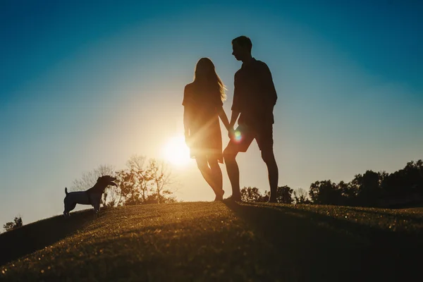 Silhouette due ragazza e giovane uomo che si tiene per mano — Foto Stock