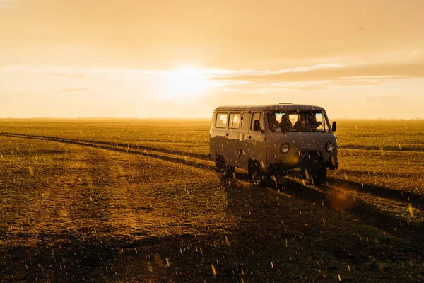 Eski bir Sovyet off-road aracı olan UAZ, bir kır yolunda otobüs turu yapıyor. Sıcak, güzel bir gün batımı sepya ışığı ve yağmur. Arka ışık. Romantik nostaljik sinema filmi. Macera ruhu  