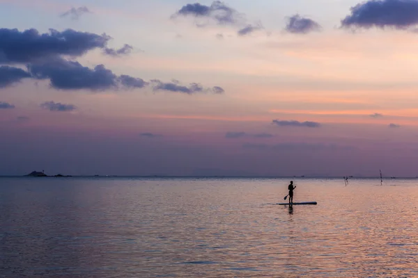 Один чоловік плаває у воді на тлі прекрасного заходу сонця — стокове фото