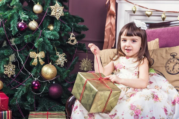 Menina bonita com curiosidade abre uma caixa com uma surpresa do presente — Fotografia de Stock