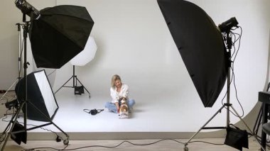 Sarışın kadın fotoğrafçı ve köpek Jack Russell Terrier beyaz siklonamayla mutlu fotoğraf stüdyosuna sarılıyorlar. Köpek öpüyor ve kuyruğunu sallıyor. Aşk ve Hayran Hayvan Sahibi 'nin video görüntüleri. Mutlu an