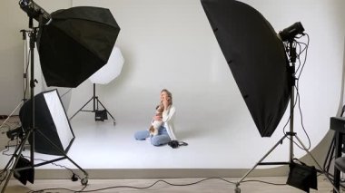 Sarışın kadın, beyaz siklonama fotoğraf stüdyosunda oturuyor, profesyonel kamerayla selfie çekiyor, sarılıyor, öpüyor, mutlu köpek Jack Russell Terrier Maya 'yı öpüyor. profesyonel fotoğrafçılık ekipmanları video görüntüsü gösterdi