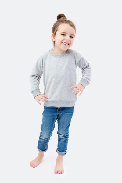 Uma menina fica em fundo cinza . — Fotografia de Stock