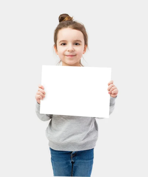 Flicka som håller en vit platta på en grå bakgrund — Stockfoto