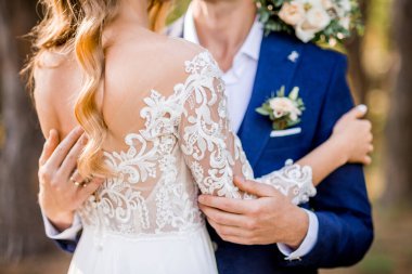 Damat gelini kucaklıyor. Arkadan bir fotoğraf. Dantelli güzel elbise.