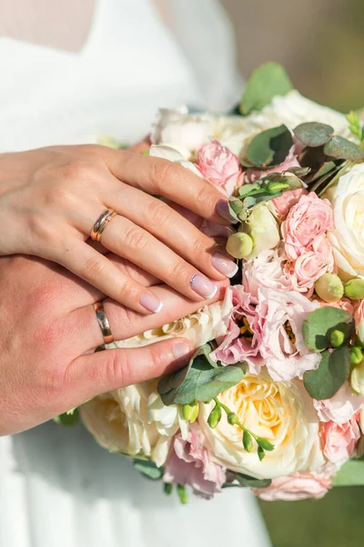 結婚指輪で手を閉じて 結婚式の花束の背景に新婚夫婦の手 — ストック写真