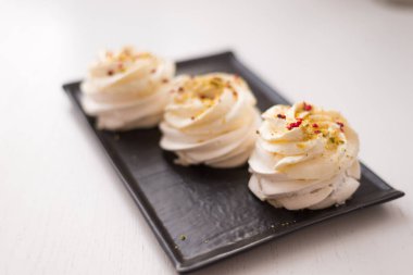 Siyah tabakta kremalı pasta. Beyaz arka planda Pavlova tatlısı. Seçici odak..