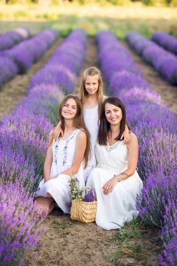 Anne ve kızları lavanta tarlasında. Mor renkli yaz fotoğrafı.
