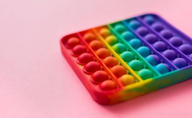 Anti-stress pop it a toy. Rainbow touch fidget spinner, on pink background. New fashion silicone toy.
