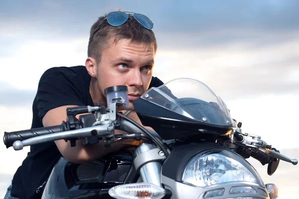 Uomo con un look testardo appoggiato sul volante della sua moto — Foto Stock