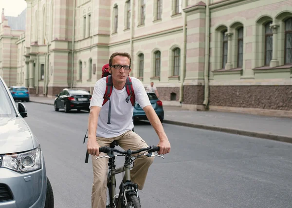 Tourist man on a bike at city street — Stock Photo, Image