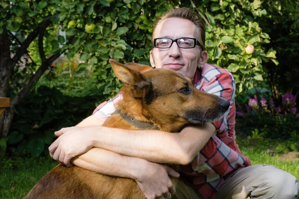 Man och hans hund vila i trädgården — Stockfoto