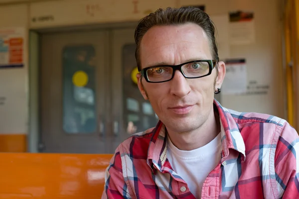 Young man sitting in train looking at camera — Stock Photo, Image