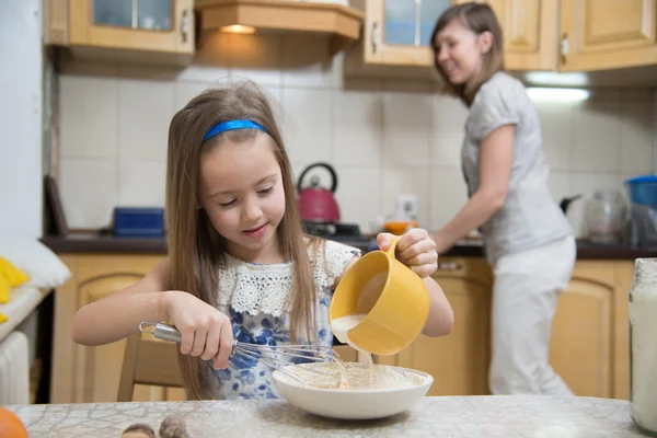 Small girl going to beat the dough for pancakes