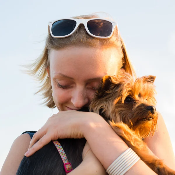 Hermosa joven feliz mujer con pelo rubio sosteniendo perro pequeño — Foto de Stock
