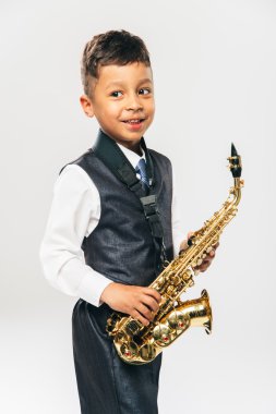 six years old boy plays saxophone at studio clipart