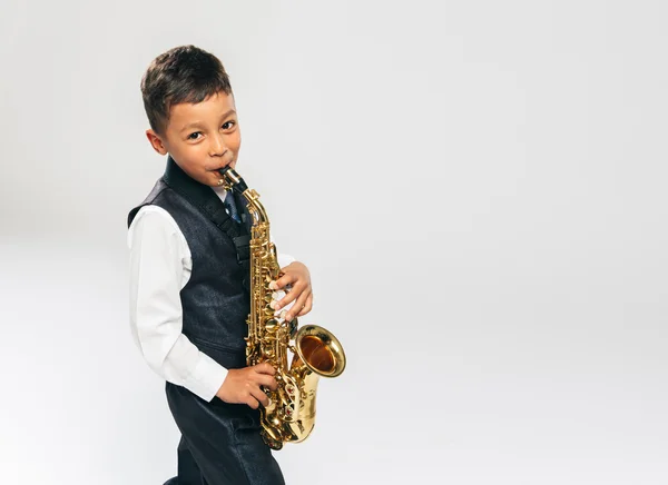 Niño de seis años toca el saxofón en el estudio Fotos de stock libres de derechos