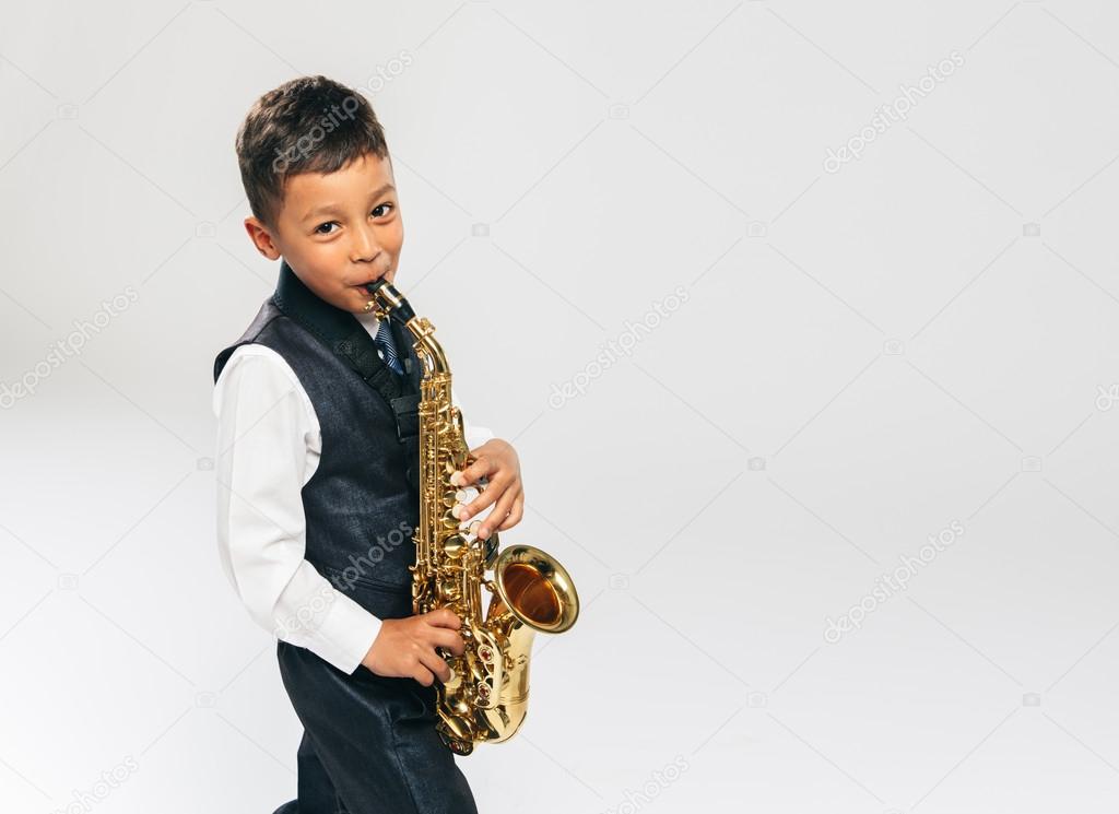 six years old boy plays saxophone at studio