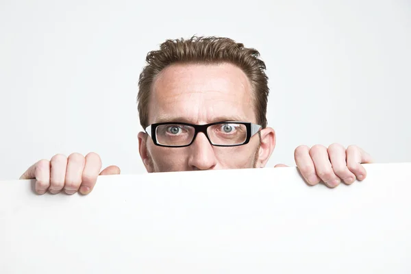 Man in eyeglasses peep from the white board. . — Stock Photo, Image