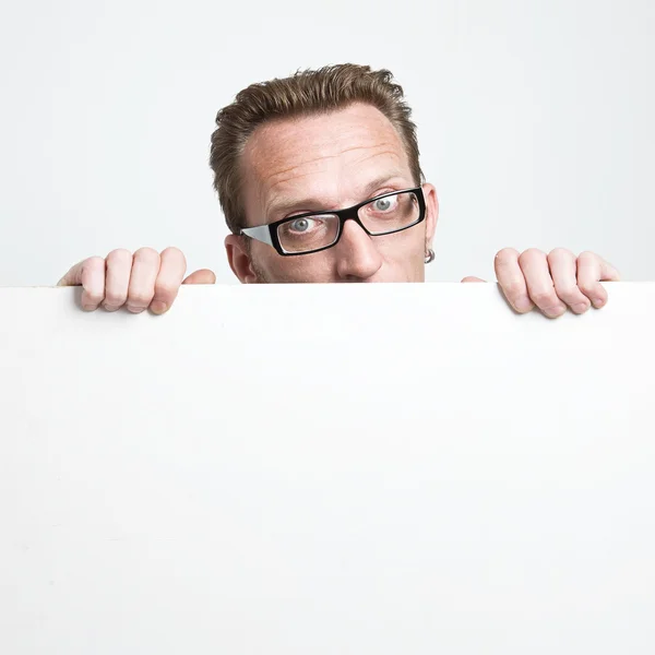 Man in eyeglasses peep from the white board. . — Stock Photo, Image