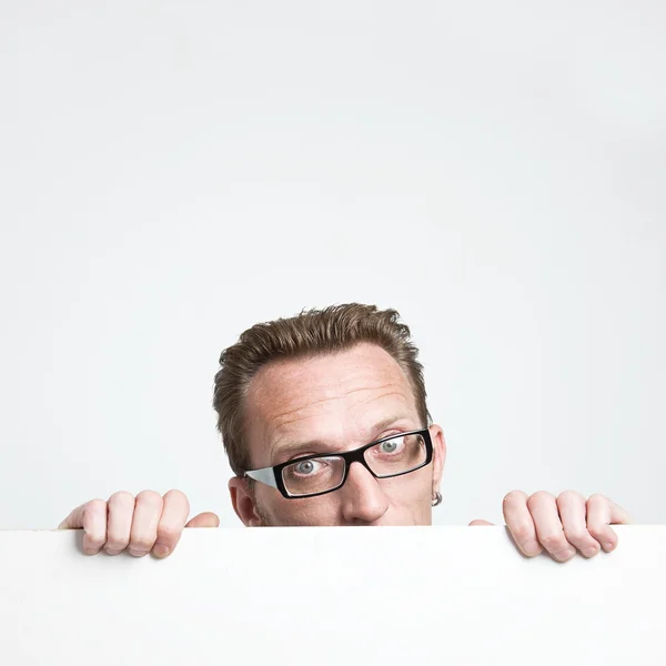 Man in eyeglasses peep from the white board. . — Stock Photo, Image