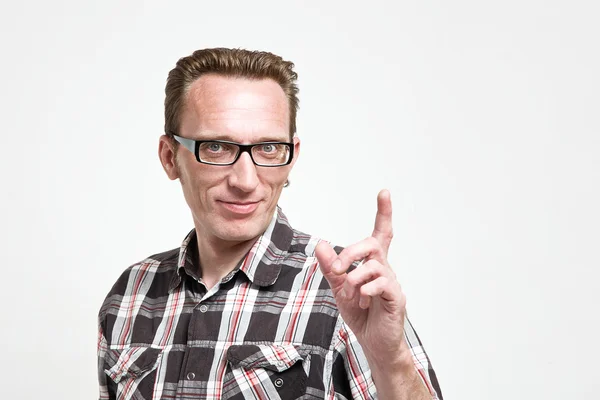 Handsome man in eyeglasses and tartan shirt put his index finger up. — Stock Photo, Image