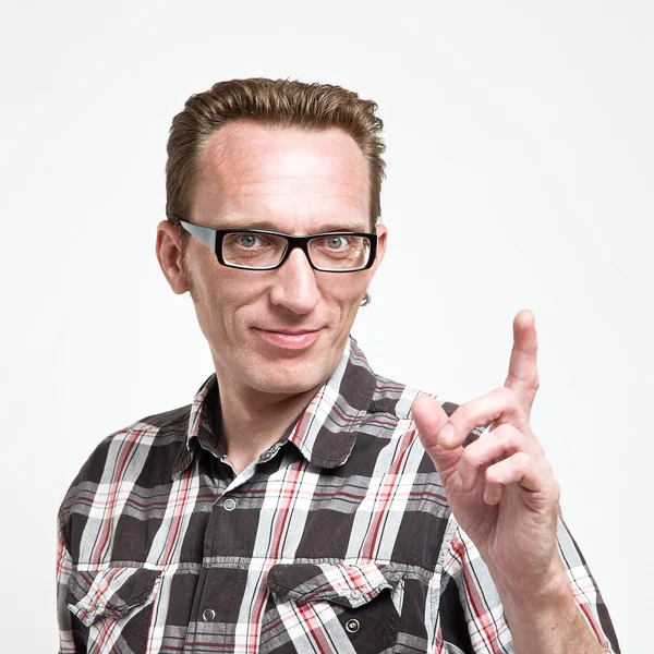 Handsome man in eyeglasses and tartan shirt put his index finger up. — Stock Photo, Image