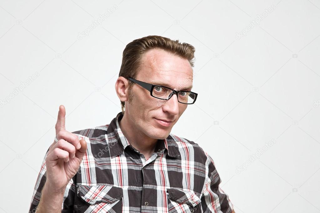 Handsome man in eyeglasses and tartan shirt put his index finger up.  