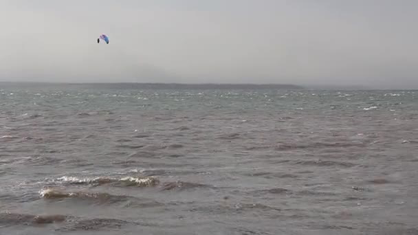 Kite surfing. Surfing with a sail in the wind. Strong storm at sea and a man riding the waves. — Stock Video