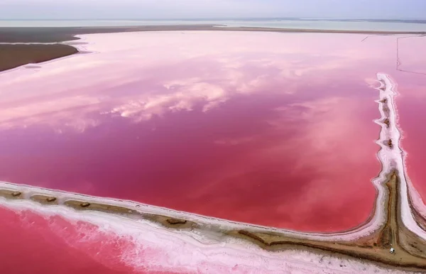 Rózsaszín tó és part a víz mentén. Az égi felhők tükröződése rózsaszín vízben. — Stock Fotó