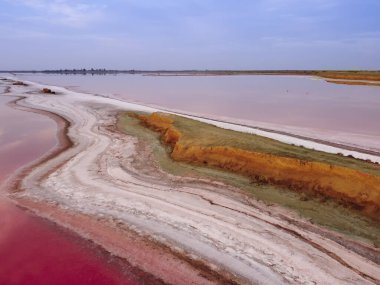 Pembe bir göl manzarası. Göl ile deniz koyunu ayıran dar kıyı. Yüksek tuz içerikli pembe göl.