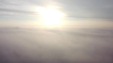 Sabah bulutlarının üzerinde bir dronun yükselişi. Sisin içinden gün ışığı doğuyor..